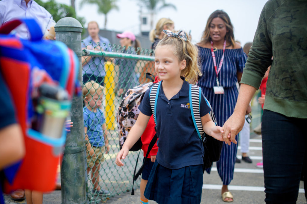 SFC kindergarten student walks hand-in-hand with an SFC staff member.