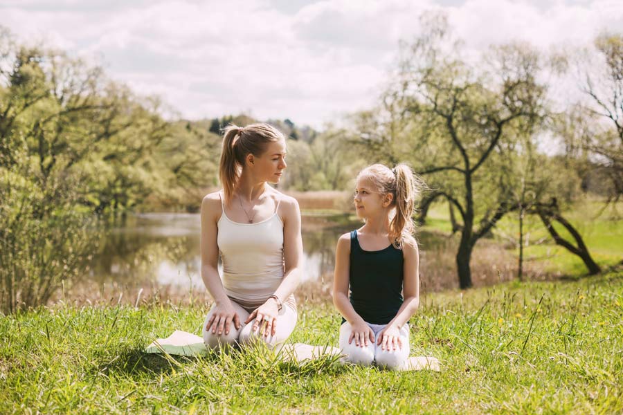 mother and daughter doing outside meditation