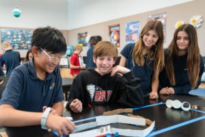Four middle schoolers work together to build a track for a small robot to use.